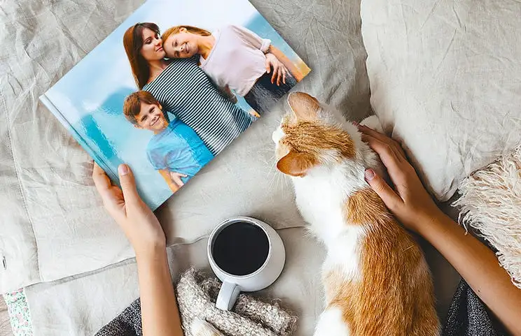 Gelijk met een fotoalbum met gepersonaliseerde familiefoto's op schoot, genietend van een kop koffie.